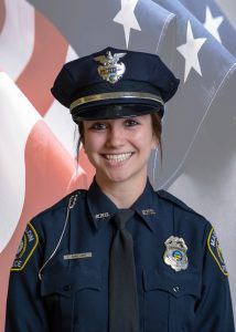 woman in a police uniform in front of a flag