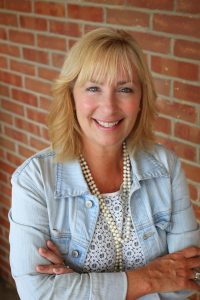 Woman with blonde hair in front of brick wall